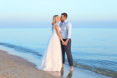 Wedding couple. Groom kissing bride on beach