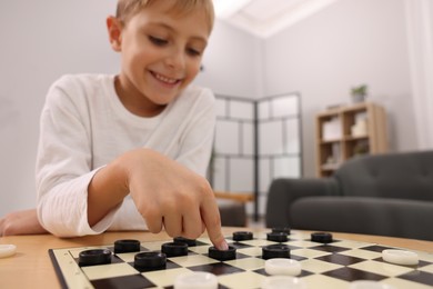 Photo of Boy playing checkers at home, selective focus