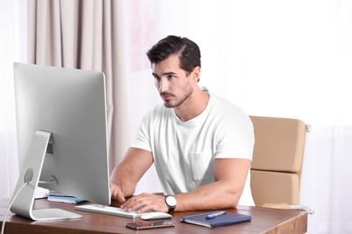 Handsome young man working with computer at table in office