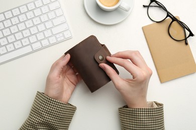 Photo of Woman holding leather card holder at white table, top view