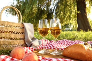 Photo of Picnic blanket with delicious food and wine in park on sunny day