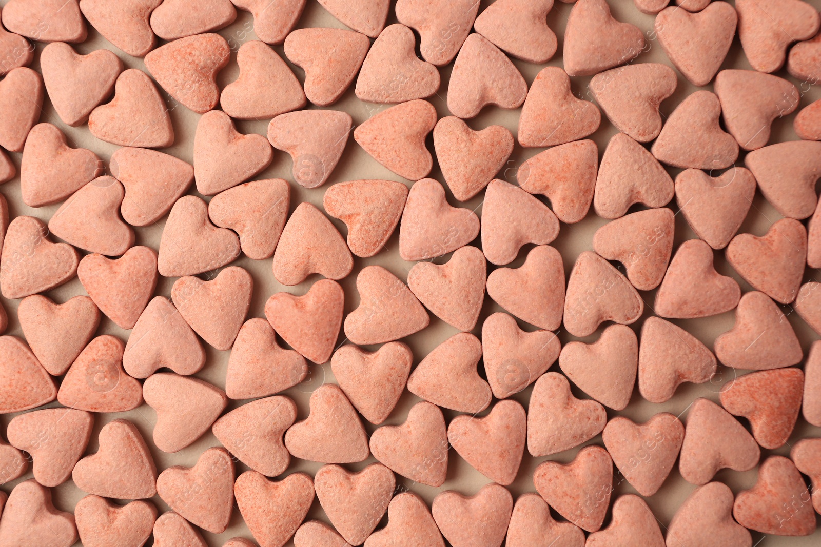 Photo of Many heart shaped vitamins for pets on beige background, flat lay