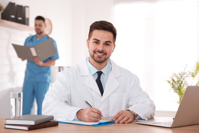 Portrait of male doctor at table in modern clinic