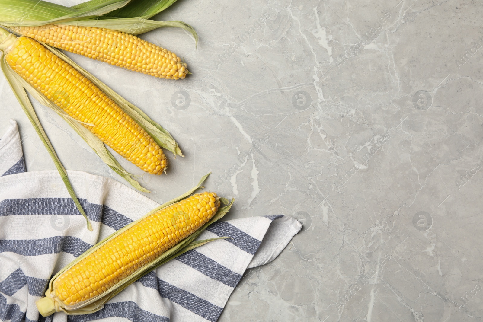Photo of Corn cobs on marble table, flat lay. Space for text
