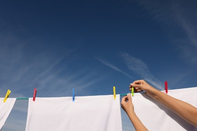 Photo of Woman putting clothes pins on laundry line outdoors, closeup. Space for text