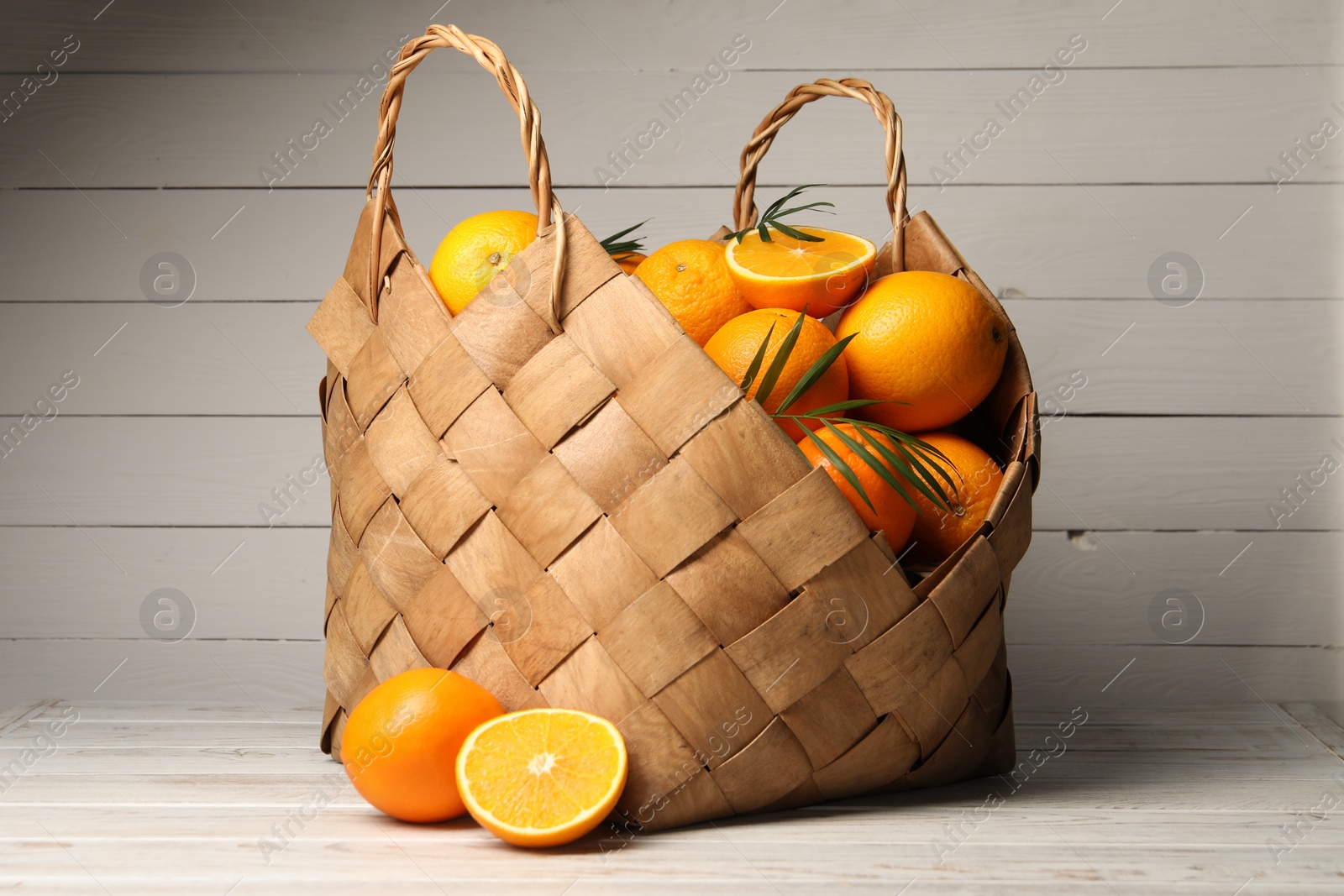 Photo of Many whole and cut oranges on white wooden table