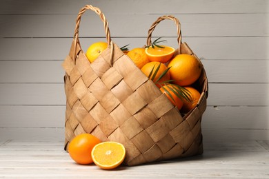 Photo of Many whole and cut oranges on white wooden table