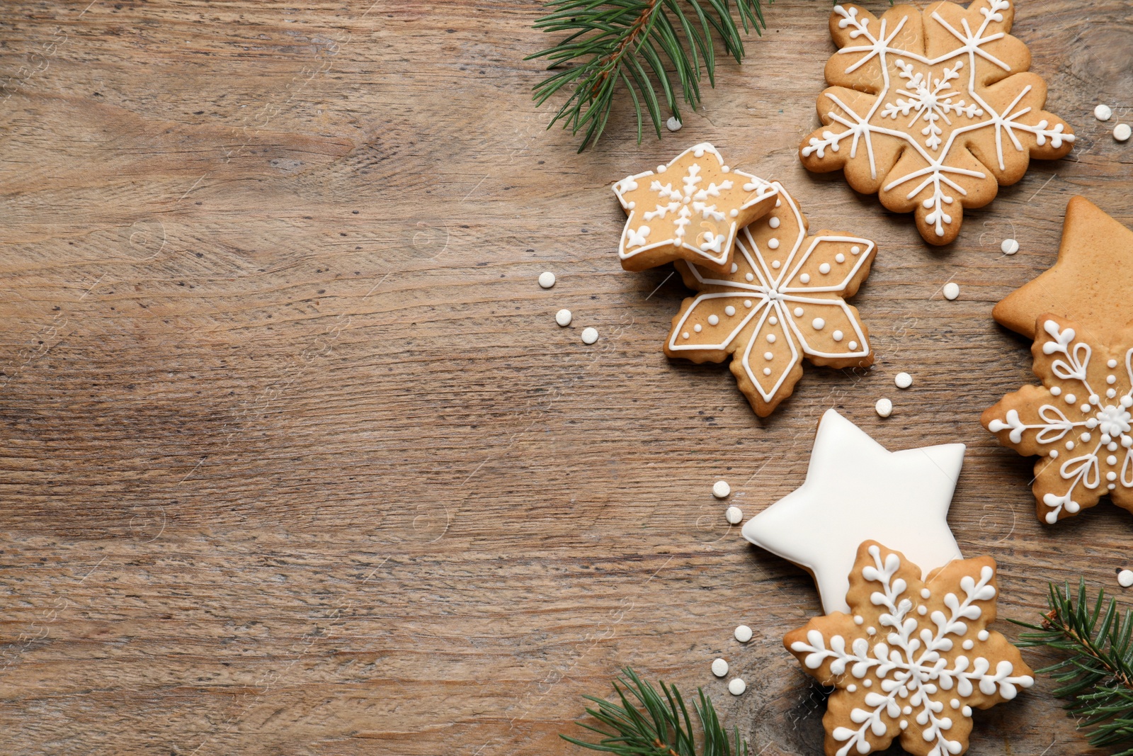 Photo of Tasty Christmas cookies and fir branches on wooden table, flat lay. Space for text