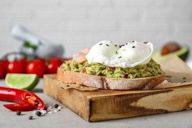 Delicious sandwich with guacamole, shrimps and fried egg on light grey table, closeup