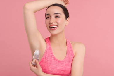 Photo of Beautiful woman applying deodorant on pink background