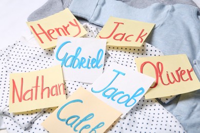 Photo of Many sticky notes with different baby names on child's clothes, closeup