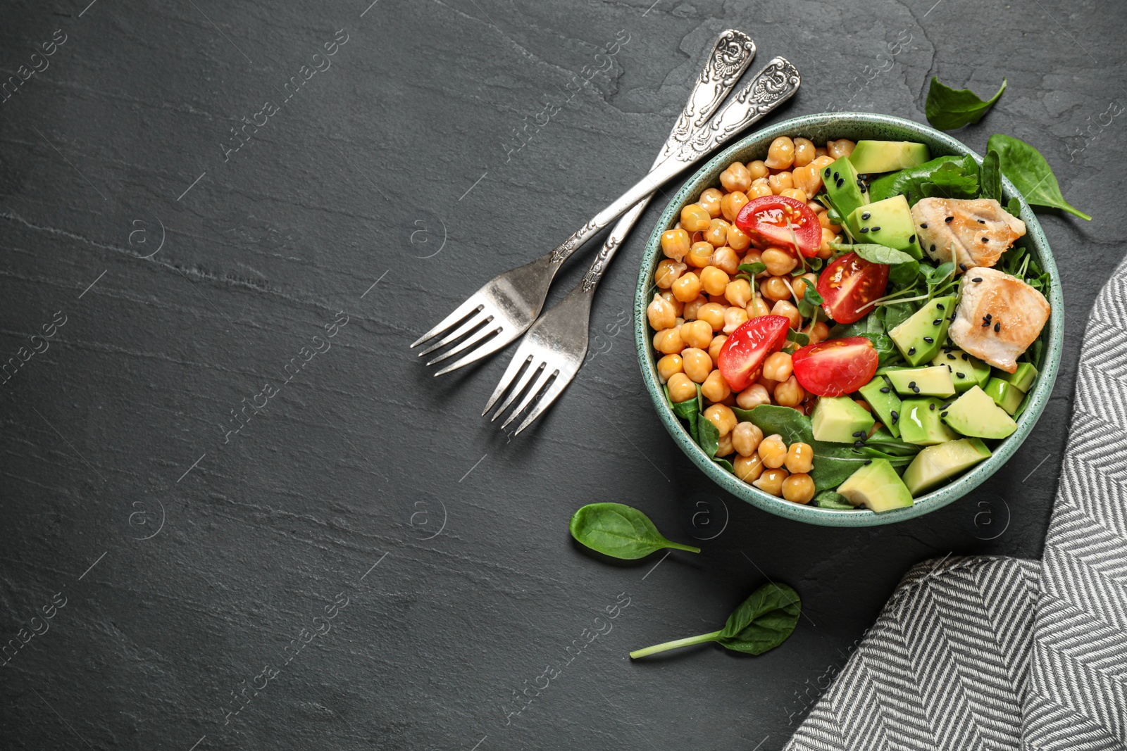 Photo of Delicious avocado salad with chickpea on black table, flat lay. Space for text