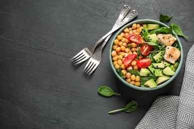 Delicious avocado salad with chickpea on black table, flat lay. Space for text