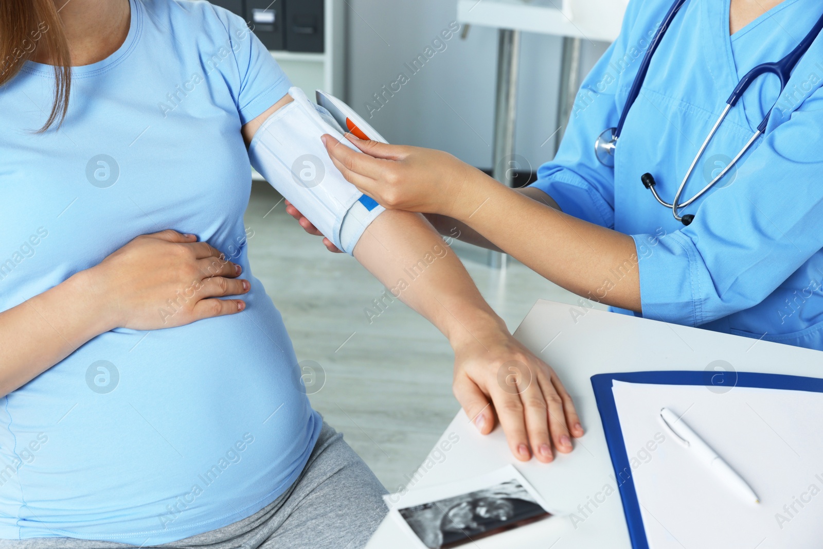 Photo of Doctor measuring blood pressure of pregnant woman in hospital, closeup