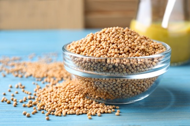 Mustard seeds in glass bowl on turquoise wooden table, closeup