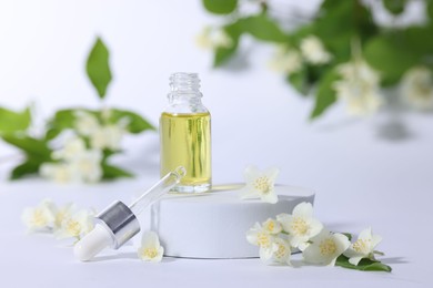 Presentation of essential oil in bottle and beautiful jasmine flowers on white background