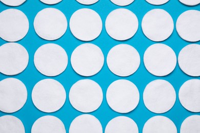 Many cotton pads on light blue background, flat lay