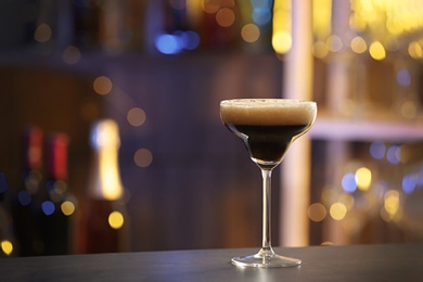 Photo of Glass of Espresso Martini on counter in bar, space for text. Alcohol cocktail