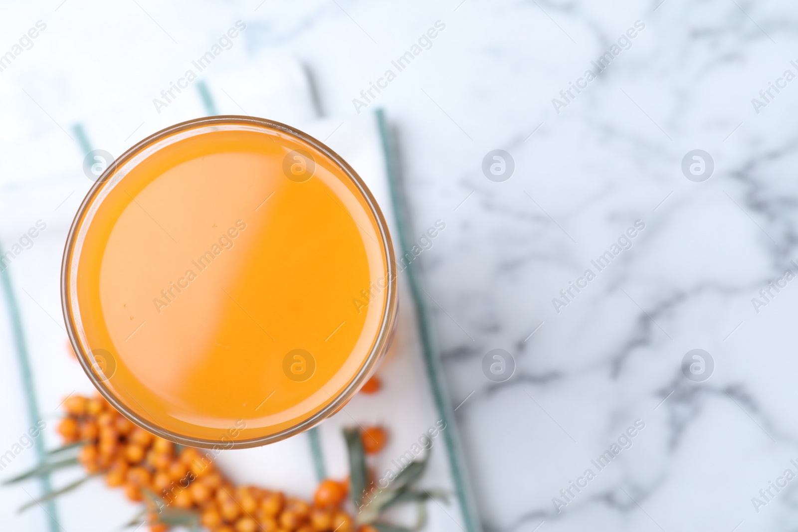 Photo of Delicious sea buckthorn juice on white marble table, top view. Space for text