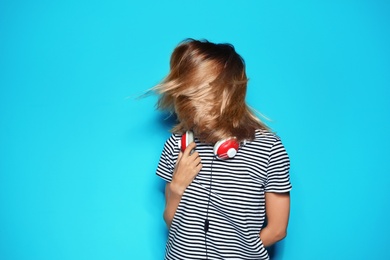 Beautiful young woman with healthy long blonde hair and headphones on color background