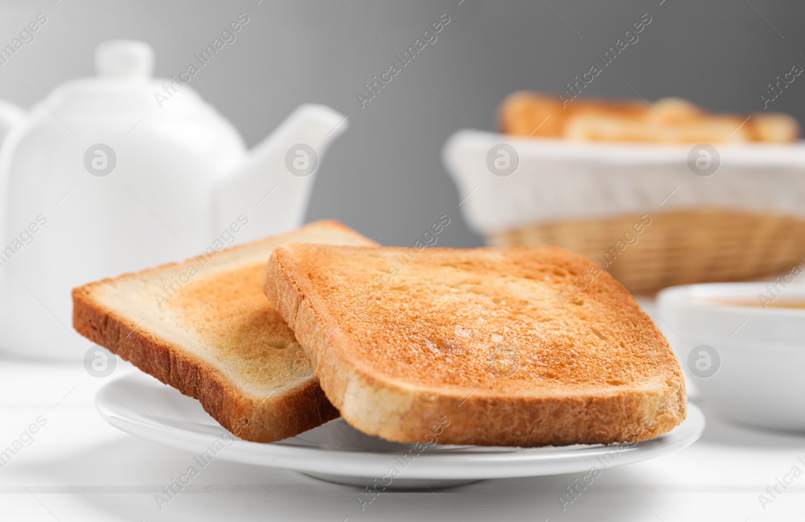 Photo of Slices of tasty toasted bread on white wooden table, closeup