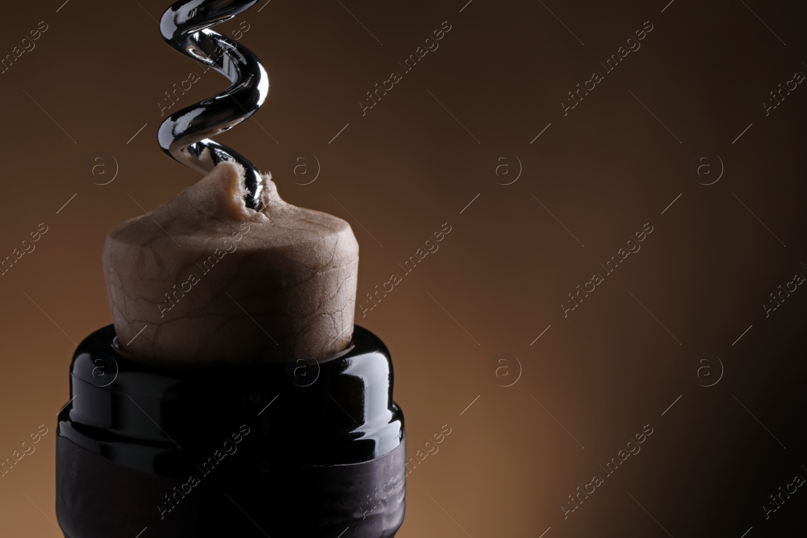 Photo of Opening wine bottle with corkscrew on dark brown background, closeup. Space for text