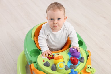 Photo of Portrait of cute little boy in baby walker on wooden floor