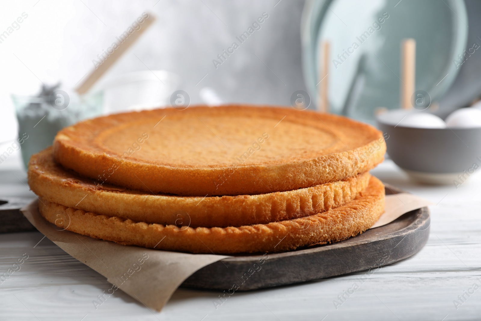 Photo of Delicious homemade sponge cakes and ingredients on white wooden table, closeup