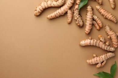 Many raw turmeric roots on light brown table, flat lay. Space for text