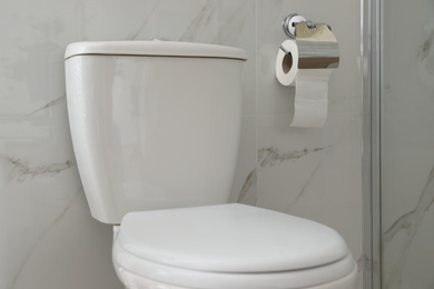 Modern toilet and holder with paper roll indoors