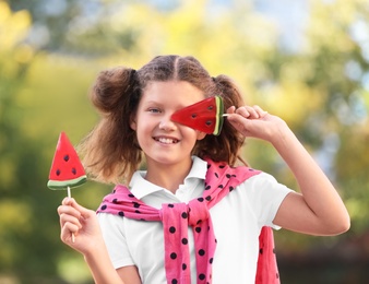 Photo of Cute little girl with tasty candies outdoors