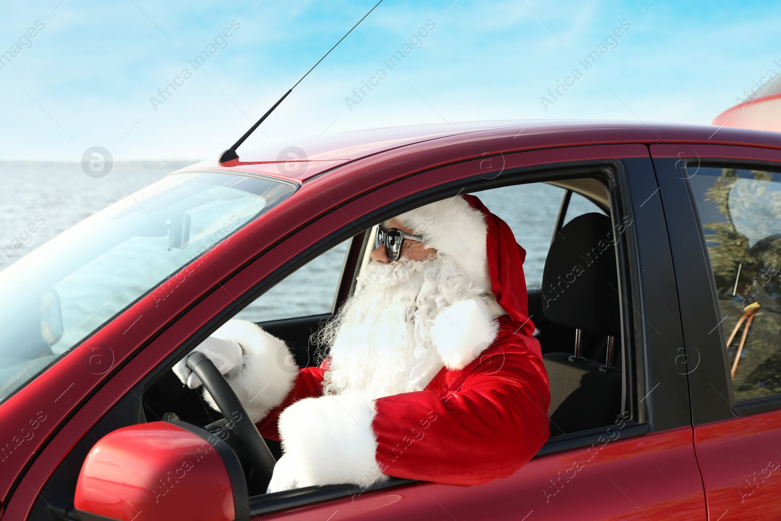 Photo of Authentic Santa Claus with sunglasses driving car, view from outside