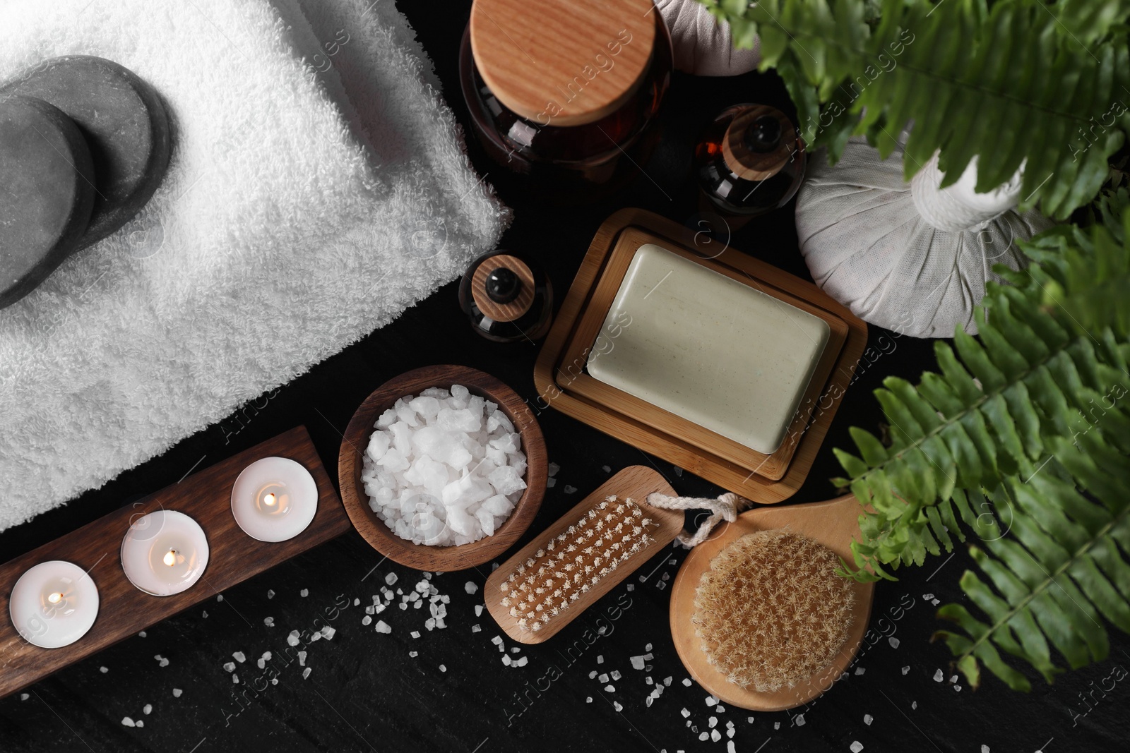 Photo of Flat lay composition with different spa products and burning candles on black table