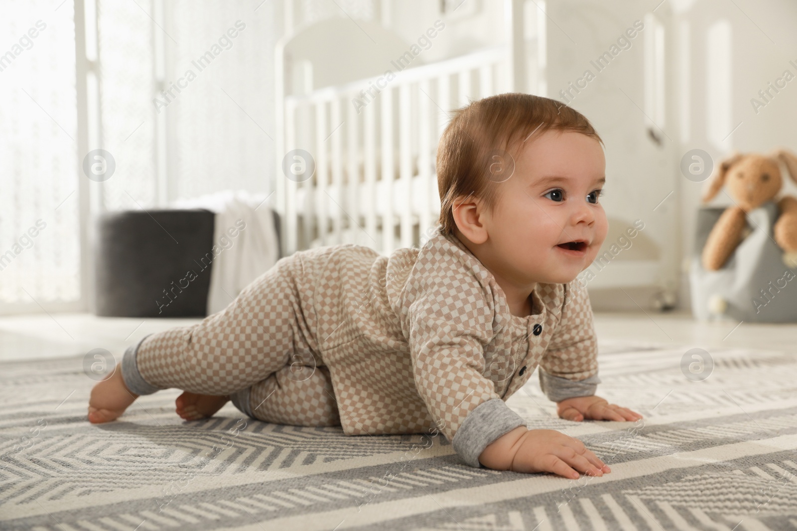 Photo of Cute baby crawling on floor at home