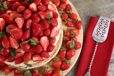 Tasty cake with fresh strawberries and mint served on gray table, above view