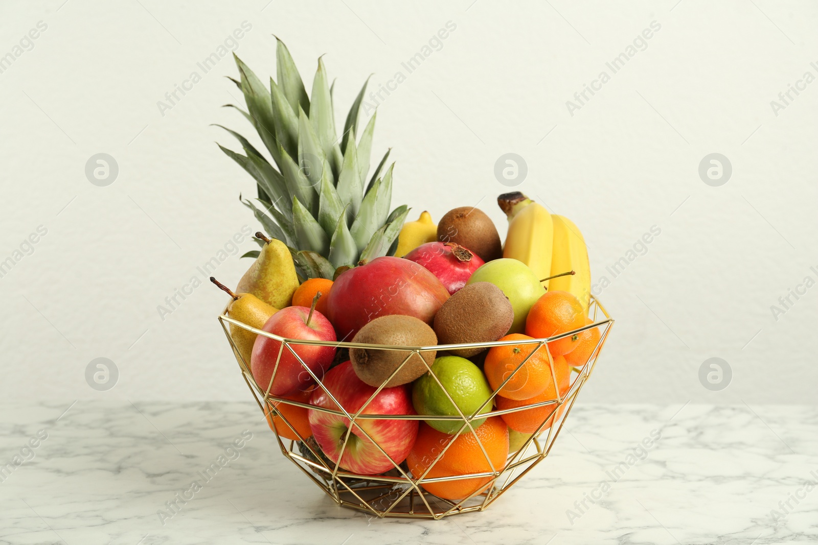 Photo of Metal bowl with different fresh fruits on white marble table