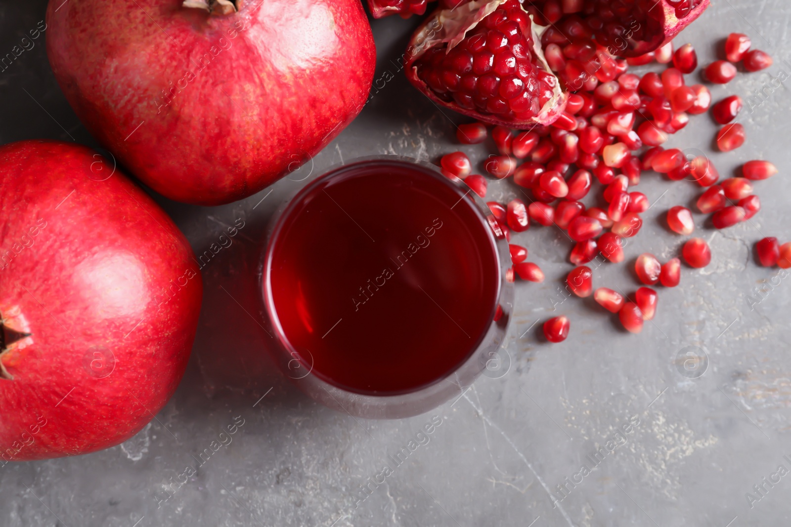 Photo of Flat lay composition with glass of fresh pomegranate juice and fruits on grey background