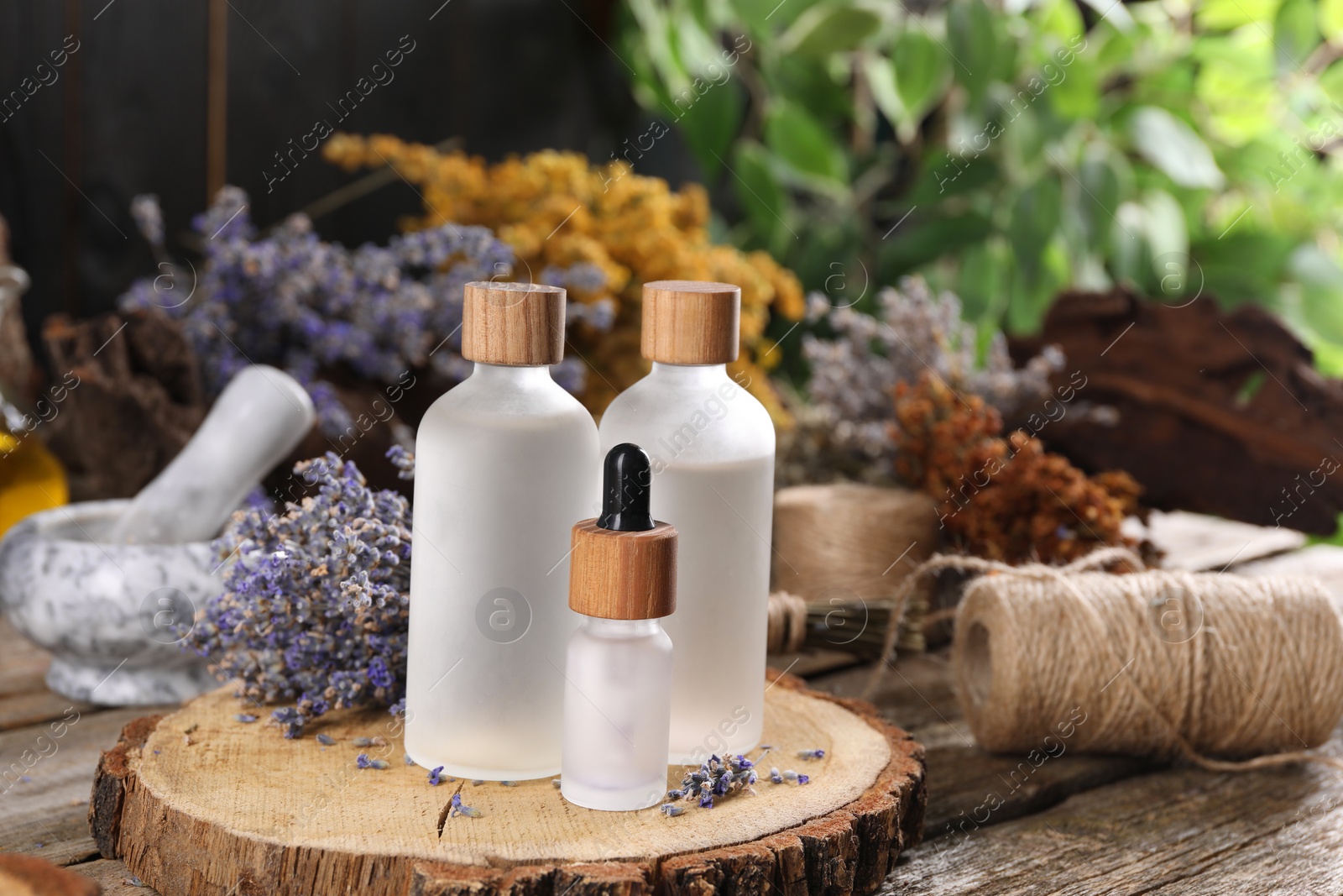 Photo of Bottles of essential oils and dry lavender flowers on wooden table. Medicinal herbs