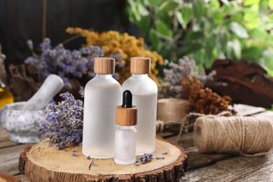 Photo of Bottles of essential oils and dry lavender flowers on wooden table. Medicinal herbs