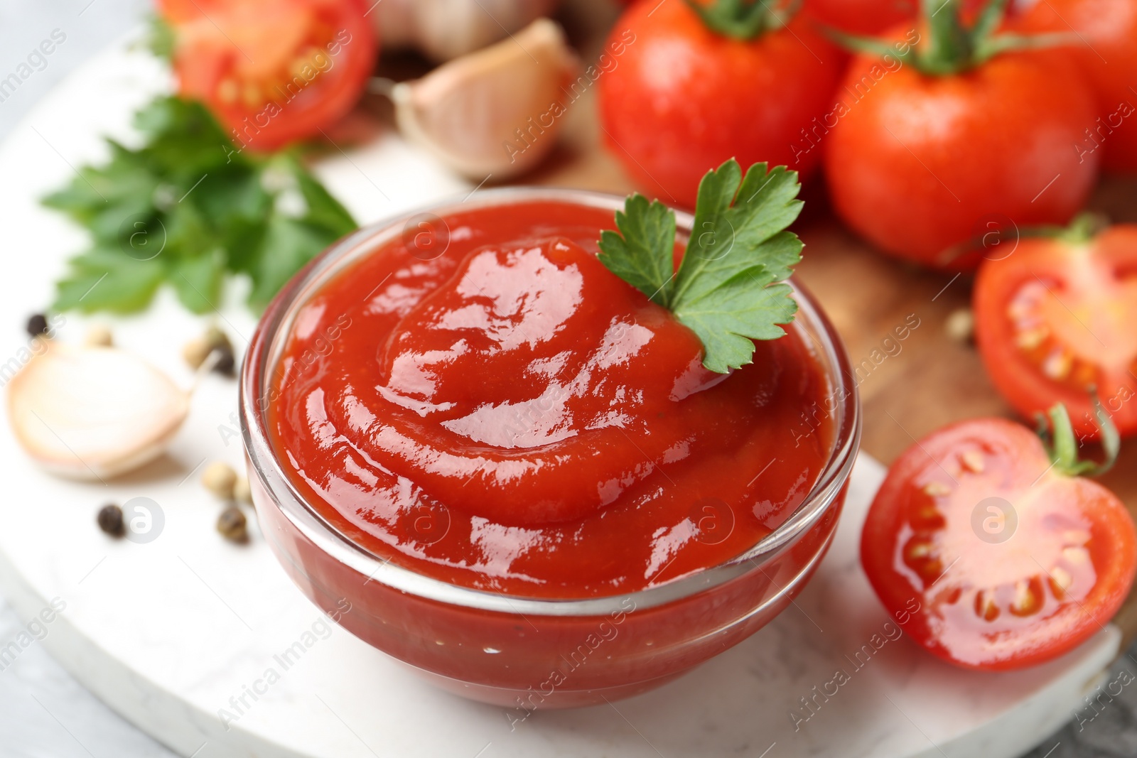 Photo of Delicious tomato ketchup and parsley in bowl on light table, closeup