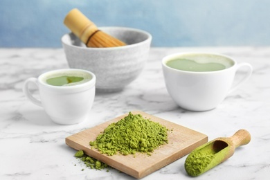 Photo of Wooden board and scoop with powdered matcha tea on table