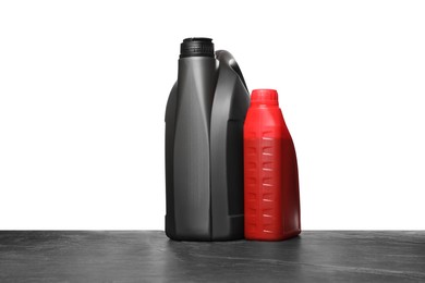 Photo of Motor oil in different canisters on black table against white background
