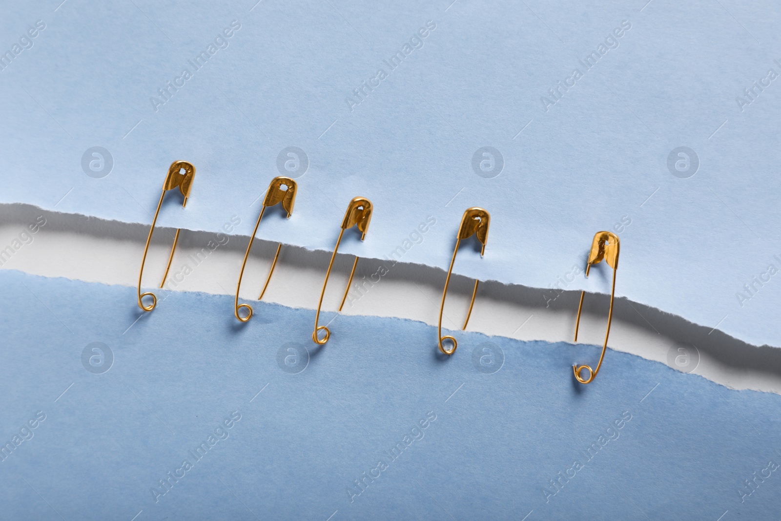 Photo of Pieces of paper sheets joined with safety pins on white background, top view