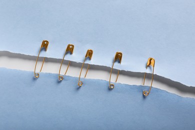 Pieces of paper sheets joined with safety pins on white background, top view