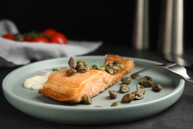 Delicious salmon with capers and sauce served on dark table, closeup