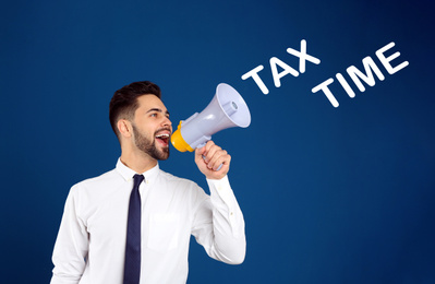 Young man with megaphone and text TAX TIME on blue background