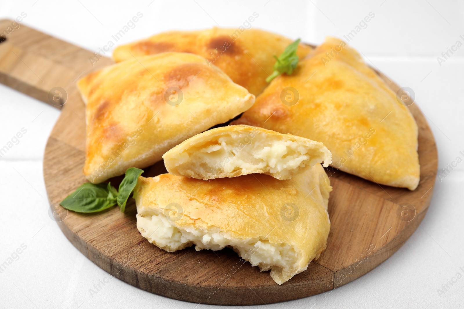 Photo of Delicious samosas and basil on white tiled table, closeup