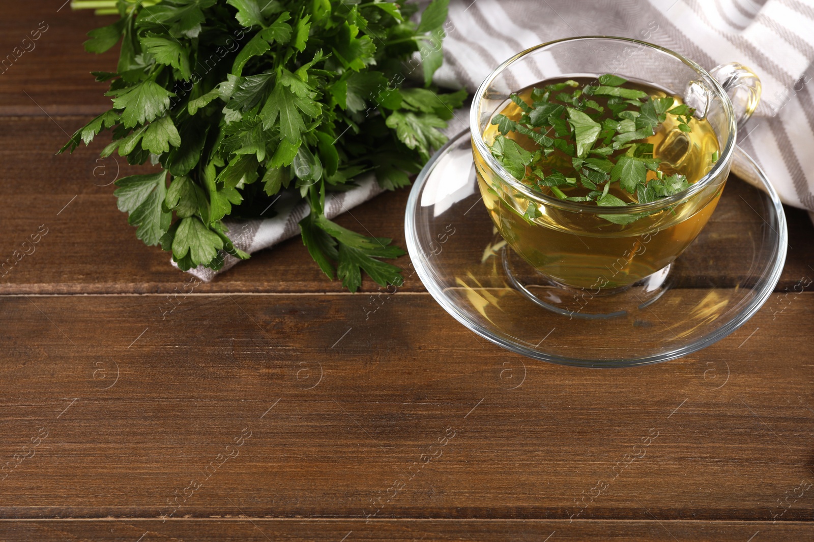 Photo of Aromatic herbal tea and fresh parsley on wooden table, space for text