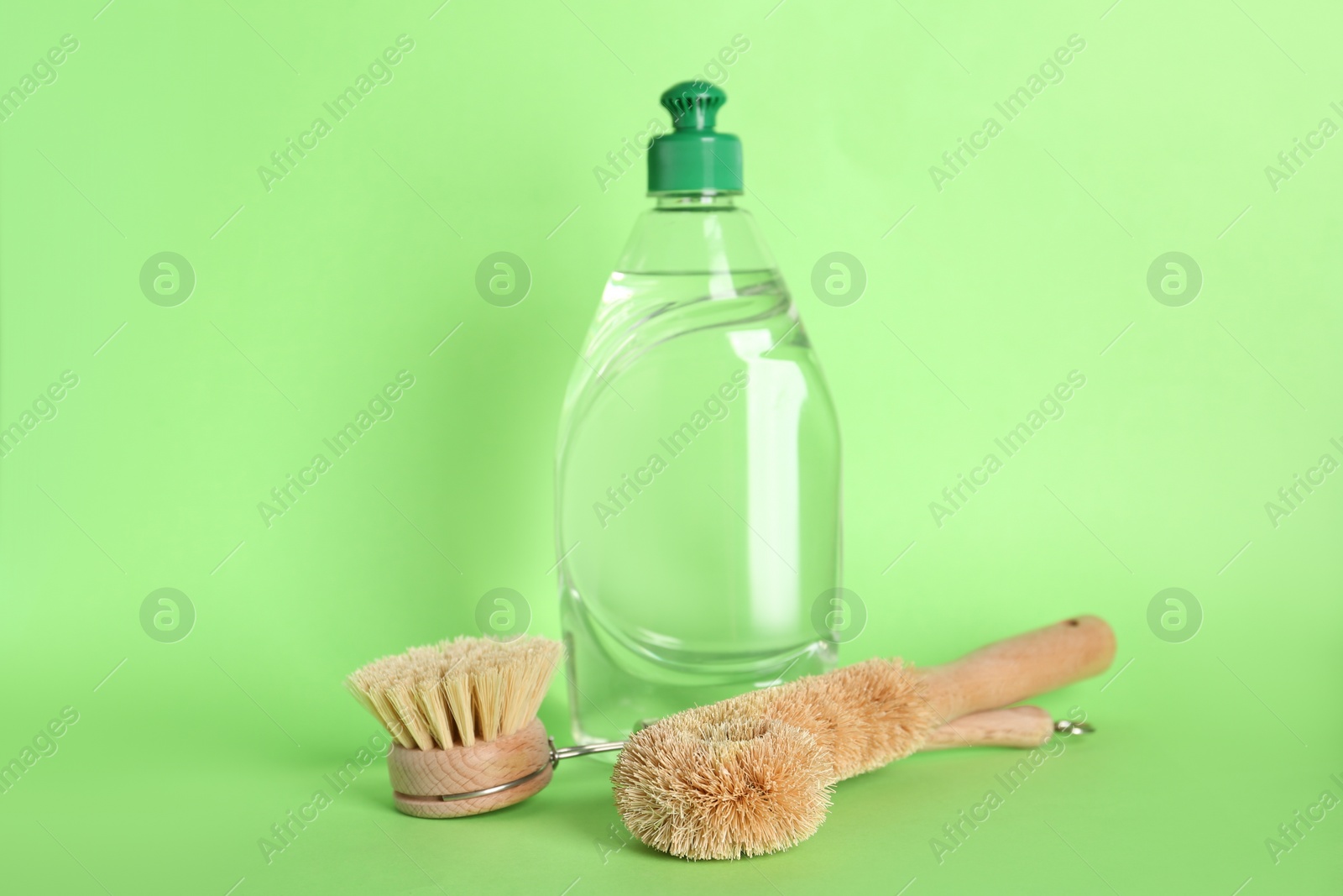 Photo of Cleaning product and brushes for dish washing on green background