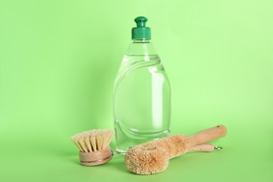 Photo of Cleaning product and brushes for dish washing on green background